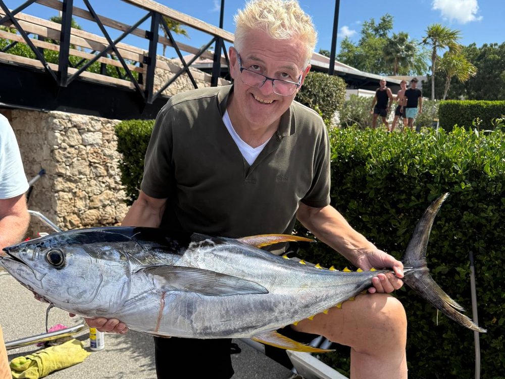 Angler holding a yellowfin tuna at the waterfront, Bonaire