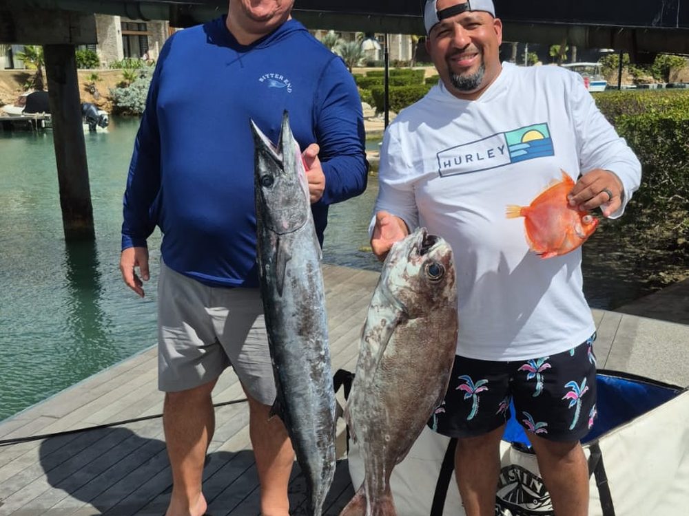 Two guests on the dock with a wahoo and reef fish